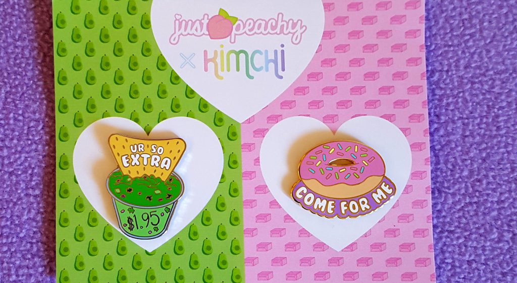 Starting an Art Business a set of 2 food pins from KimChi and Just Peachy on a wide, green and pink backing card. One pin is a chip dipped into guacamole that reads "You're so extra" and the other is a donut with the words "come for me" below it. Donut come for me.